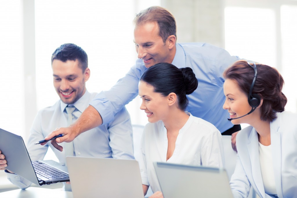 boss instructing employees with laptops