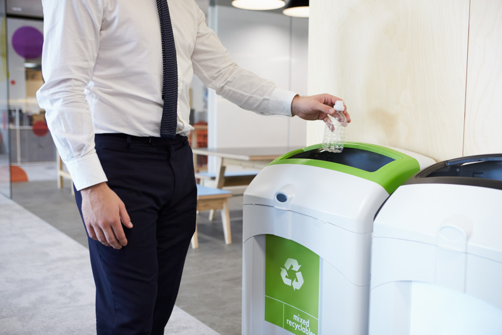employee throwing trash on a recycle bin