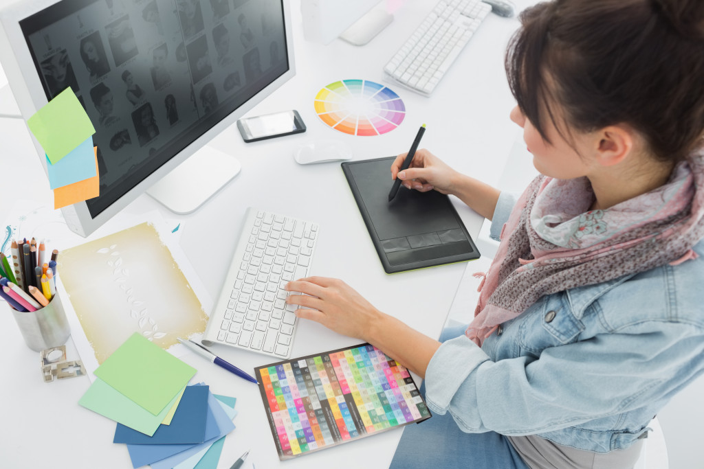 female digital artist using drawing tablet with pen and computer in white office